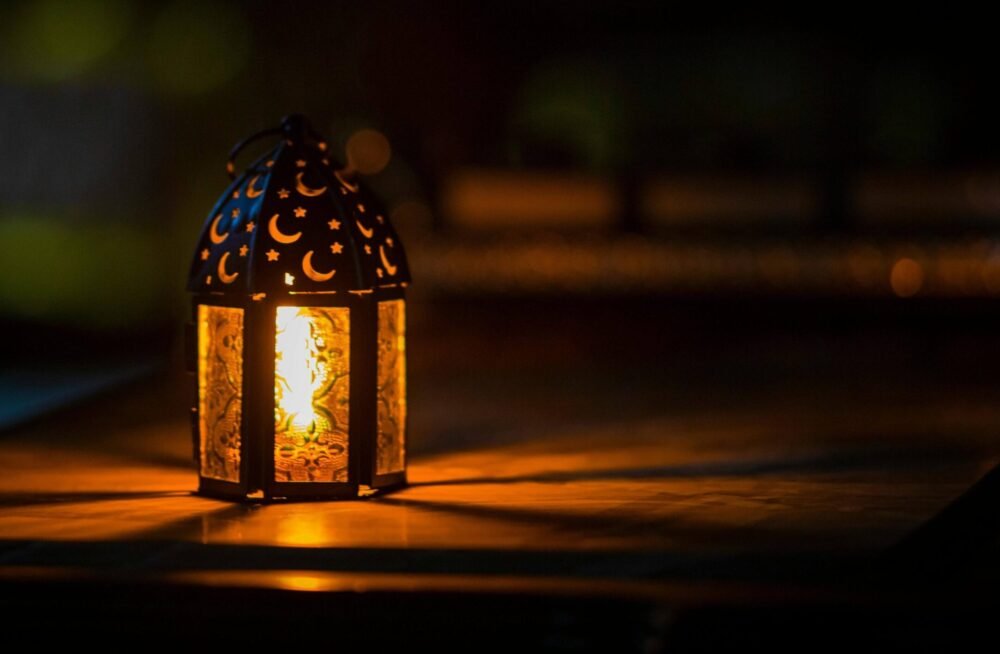 A lit lantern kept in dark. The dim light is spreading a golden light.