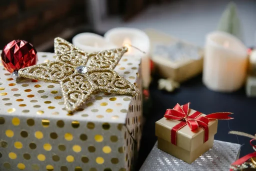 A picture focused on a golden star. Some wrapped gifts and candles are also there.