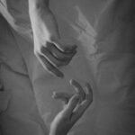 A black and white picture, two hand trying to touch each other's hand creating a distance.