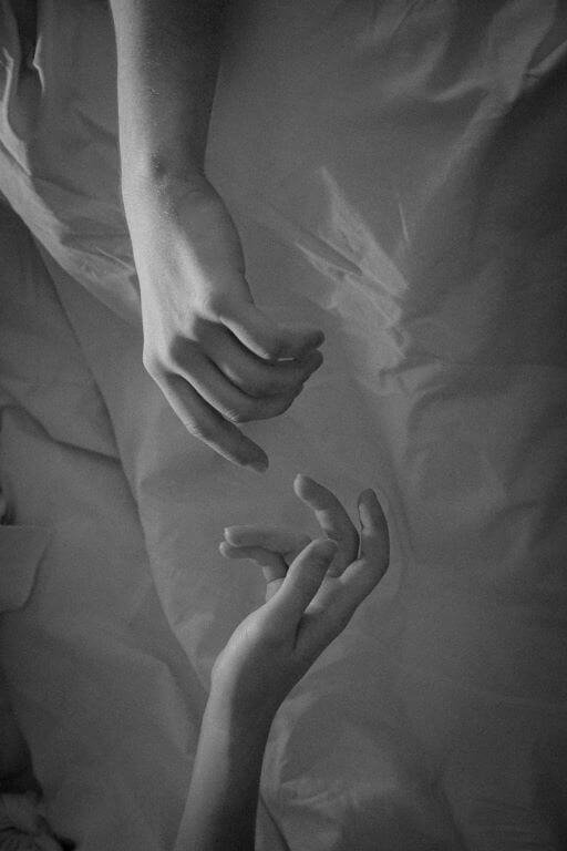 A black and white picture, two hand trying to touch each other's hand creating a distance.