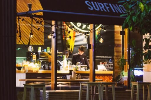 A bright picture of a cafe with lots of lights. A boy is working there.