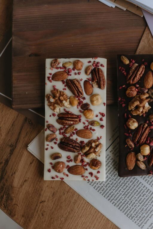 A chocolate bar with lots of dry fruits on top like nuts, dates.