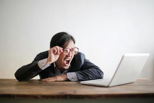 A man is frustratingly looking at the laptop holding his glasses. A funny expression that shows he has made some mistakes.